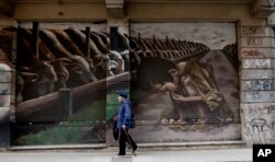 FILE - A photo shows a mural titled "Hunger Games" by artist El Marian, featuring a starving boy huddling next to cattle eating grain in Buenos Aires, Argentina, Oct. 5, 2016.