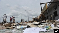 Resident walk past shops looted and destroyed in the Abobo district of Abidjan, March 2, 2011