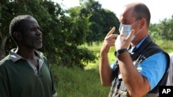 In this April 4, 2019 photo, Stephen Fonseca, right, gives a community leader guidance on handling the dead in Magaru, Mozambique.