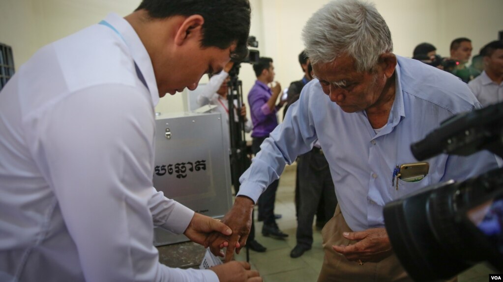 រូបឯកសារ៖ មន្ត្រី​ការិយាល័យ​បោះឆ្នោត​កាន់​ដៃ​ក្រុម​ប្រឹក្សា​​សង្កាត់​មួយរូប​ជ្រលក់​ទឹក​ថ្នាំ​ បន្ទាប់​ពី​បាន​បោះ​ឆ្នោត​ព្រឹទ្ធ​សភា ​នៅ​ភ្នំពេញ ​កាល​ពី​ថ្ងៃទី២៥ ​ខែកុម្ភៈ ​ឆ្នាំ២០១៨។ ​(អូន ឆេងប៉រ/VOA) 