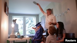 Doug Hassebroek pours confetti over his daughter Lydia, celebrating her graduation ceremony at their home during the outbreak of coronavirus disease (COVID-19) in Brooklyn, New York, U.S., June 17, 2020. 