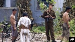 A North Korean soldier chats with a villager while doing a routine guard along the waterfront of the Yalu River at the North Korean town of Sinuiju, opposite side of the Chinese border city of Dandong, China, Saturday, Aug. 18, 2007.