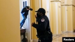 资料照片：在国会两院召开认证总统选举结果的联席会议期间，一名国会警察向一名试图进入国会大厦的抗议者喷射胡椒喷剂。(2021年1月6日)