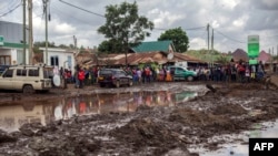 Watu wamekusanyika kufanya tathimini ya uhalibifu katika mtaa uliojaa matope kutokana na maporomoko ya aridhi na mafuriko huko Tanzania. Picha na Ebby SHABAN / AFP