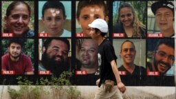Seorang pria melintas di depan poster Hersh Goldberg-Polin bersama poster sandera lainnya yang diculik dalam serangan Hamas pada 7 Oktober, di Tel Aviv, Israel, 1 September 2024. (Foto: REUTERS/Florion Goga)