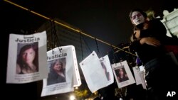 People hug next to images of murdered women following a Day of the Dead march calling for justice for victims of femicide, in Mexico City, Nov. 1, 2017. 