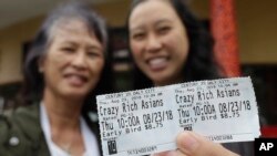 Audrey Sue-Matsumoto, right, holds tickets as she poses for photos with her mother Alice Sue while interviewed outside of a movie theater after watching the movie Crazy Rich Asians in Daly City, Calif. 