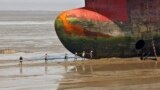 Workers carry a rope to a decommissioned ship at the Alang shipyard in the western Indian state of Gujarat.