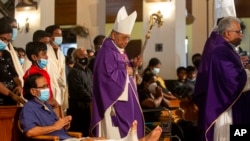 FILE - Cardinal Malcolm Ranjith, archbishop of Colombo, center, looks at a survivor of 2019 Easter Sunday attacks as he arrives to conduct a service at St. Anthony's Church in Colombo, Sri Lanka, April 21, 2021. 