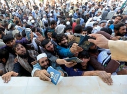 FILE - Afghan men wait to collect tokens needed to apply for the Pakistan visa, in Jalalabad, Afghanistan, Oct. 21, 2020.