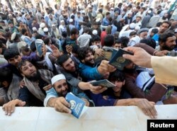 FILE - Afghan men wait to collect tokens needed to apply for the Pakistan visa, in Jalalabad, Afghanistan, Oct. 21, 2020.