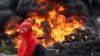 Montenegro, Cetinje, A demonstrator stands in front of a barricade set on fire during a protest against the enthronement of Bishop Joanikije