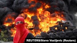 Montenegro, Cetinje, A demonstrator stands in front of a barricade set on fire during a protest against the enthronement of Bishop Joanikije