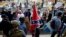 FILE - A white supremacists carries the Confederate flag as he walks past counter-demonstrators in Charlottesville, Virgina, Aug. 12, 2017.