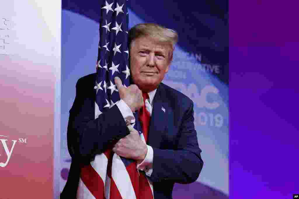 U.S. President Donald Trump hugs the American flag at the Conservative Political Action Conference in the state of Maryland on March 2, 2019. (AP Photo/Carolyn Kaster)