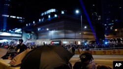 Protesters take cover as they face policemen in Hong Kong, Sept. 28, 2019.