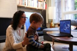 FILE - Felix Hassebroek is comforted by his mother, Naomi Hassebroek, as he reacts to the end of a livestream session with classmates he's not seen in two weeks, during the outbreak of coronavirus disease in Brooklyn, N.Y., April 3, 2020.