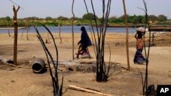 FILE - Chadian women walk past destroyed homes, in the Lake Chad shore village of N'Gouboua, March 5, 2015, following a scorched-earth attack by Boko Haram militants.