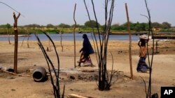 FILE - Chadian women walk past destroyed homes, in the Lake Chad shore village of N'Gouboua, March 5, 2015, following a scorched-earth attack by Boko Haram militants.