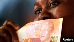 A shopper shows off South Africa's new banknotes, which features an image of former president Nelson Mandela on the front, (File photo).