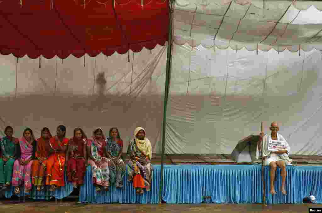 Mahesh Chaturvedi (R), 63, who dresses up like Mahatma Gandhi, sits near protesters during his day-long protest against the recent corruption scandals in India, in New Delhi, Aug. 9, 2013.