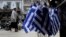 FILE - A woman walk past Greek flags for sale in central Athens, Greece as it runs perilously short of cash amid an impasse in bailout talks with its international creditors, April 22, 2015.