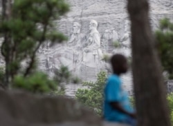 FILE - A youngster plays on a rock in front of the carving on Stone Mountain, in Stone Mountain, Ga., June 23, 2015.
