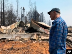 FILE - Retired teacher Charles Christianson, 67, returns to his destroyed home after a wildfire in Guerneville, Calif., Aug. 25, 2020.