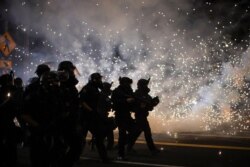 FILE - Police advance on protesters to clear a street on the 100th consecutive night of protests against police violence and racial inequality, in Portland, Oregon, Sept. 5, 2020.