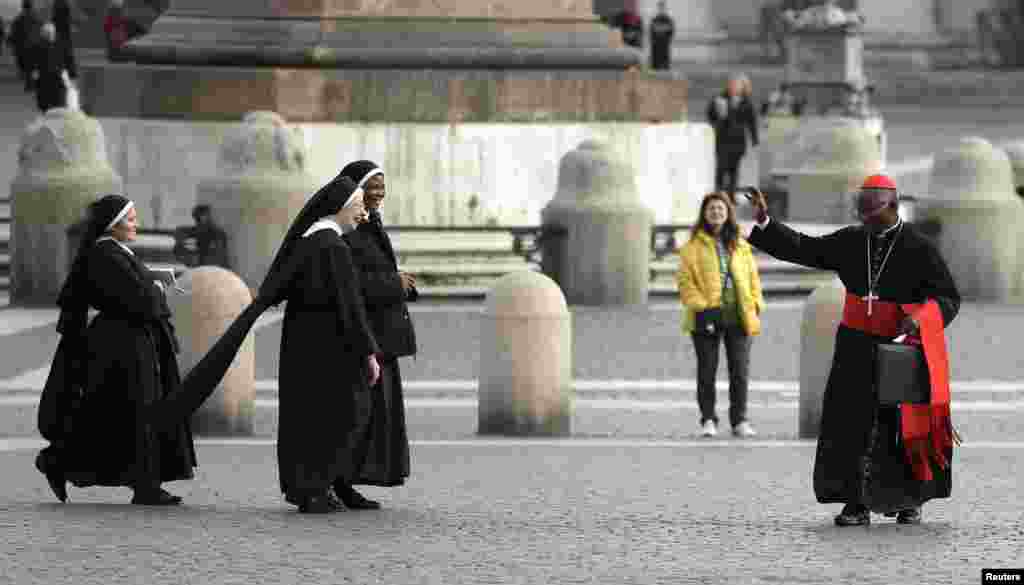 Cardinal Francis Arinze of Nigeria waves at nuns as he arrives for a meeting at the Synod Hall at the Vatican, March 8, 2013. 