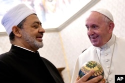 FILE - Pope Francis receives a gift from Grand Sheik Ahmed al-Tayeb, the head of Al-Azhar, left, on the occasion of their private audience at the Vatican, November 15, 2019.