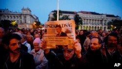 FILE - A man holds up the last printed edition of Nepszabadsag during a demonstration organized to express solidarity with the Hungarian political daily Nepszabadsag in Budapest, Hungary, Oct. 8, 2016. Mediaworks, the paper's new owner suspended 70-80 of its staffers and then dismissed most of them, bringing in pro-government editors.