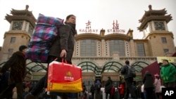 2018年2月9日，一名妇女在北京火车站外携带行李箱。中国国家统计局将此次制造业采购经理人指数下降归因于春节假期外出务工人员返乡。