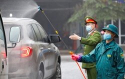 Members of anti-coronavirus team spray chemical into vehicles on a road in Thai Nguyen province, Vietnam, Feb. 7, 2020.