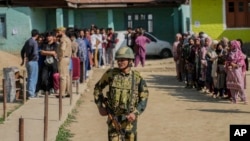 An Indian soldier stands guard as people wait to cast votes at a polling booth in Shadipora, India-administered Kashmir, on May 20, 2024. As the nation holds its national elections, India is cited as an example of the sharp curtailing of freedom of expression around the world.
