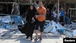 Un hombre ayuda a una mujer tras un ataque explosivo reciente en Irak.