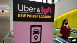 Seorang pengunjung berjalan melewati papan pengumuman yang menunjukkan area penjemputan untuk para pengguna Uber dan Lyft di Bandara Internasional Logan, di Boston, Massachusetts, pada 9 Februari 2021. (Foto: AP)