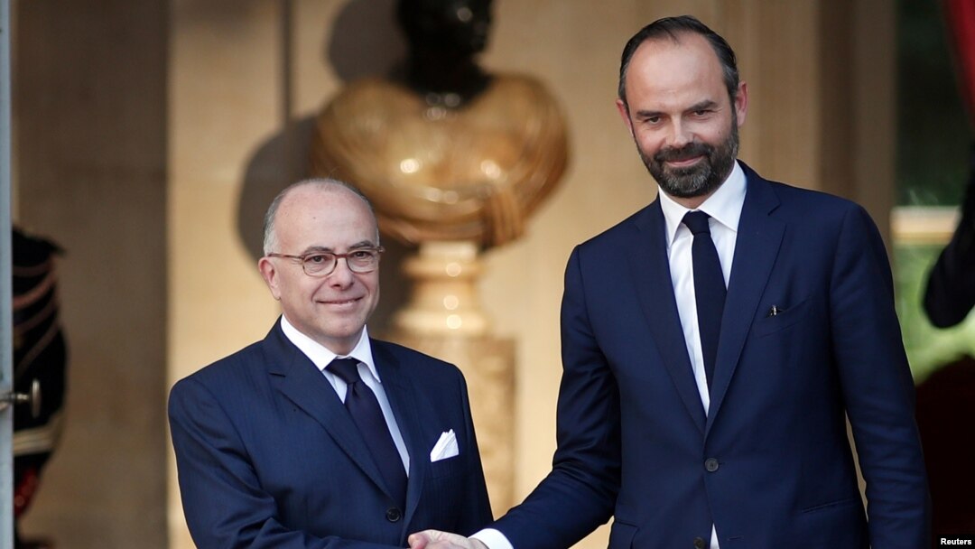 PM baru Perancis, Edouard Philippe (kanan) berjabat tangan dengan pendahulunya, mantan PM Bernard Cazeneuve pada upacara serah terima jabatan di Paris, Senin (15/5). 