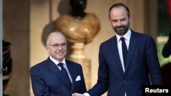 PM baru Perancis, Edouard Philippe (kanan) berjabat tangan dengan pendahulunya, mantan PM Bernard Cazeneuve pada upacara serah terima jabatan di Paris, Senin (15/5). 