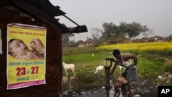 Seorang Bapak memandikan anaknya dengan air dari pompa, di samping peringatan mengenai penyakit polio di Kosi, Mathura, negara bagian Uttar Pradesh. India (foto: dok).