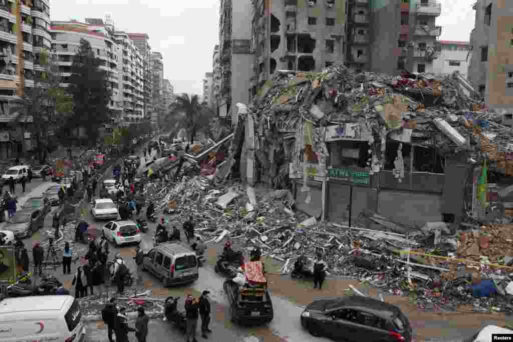 People gather as cars drive past rubble from damaged buildings in Beirut&#39;s southern suburbs, Lebanon, after a ceasefire between Israel and Iran-backed group Hezbollah took effect.