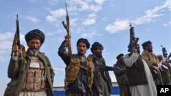 FILE - Afghan militiamen raise their weapons as they stand guard in the Achin district of Nangarhar province, Afghanistan, Dec. 27, 2015.