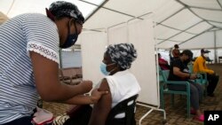 A woman receives a dose of a COVID-19 vaccine at a center, in Soweto, South Africa, Monday, Nov. 29, 2021. Scientists have warned for months that the coronavirus will thrive as long as vast parts of the world lack vaccines. (AP Photo/Denis Farrell)