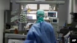 FILE - In this March 16, 2020 photo, a doctor watches a coronavirus patient under treatment in the intensive care unit of the Brescia hospital, Italy.