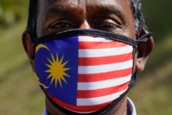 FILE - A supporter of People's Justice Party wearing a national flag face mask as he gathers with others outside the National Palace in Kuala Lumpur, Malaysia, Wednesday, Feb. 26, 2020.