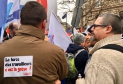 French union members gather at a recent pension strike. The sign reads, "The force of French workers is striking." (Lisa Bryant/VOA)