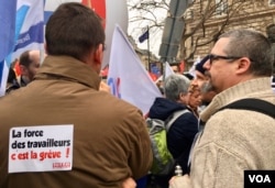 French union members gather at a recent pension strike. The sign reads, "The force of French workers is striking." (Lisa Bryant/VOA)