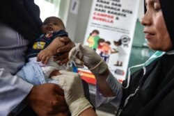 Seorang petugas medis menyuntik bayi dengan vaksin campak-rubella (MR) di sebuah posyandu di Banda Aceh, 19 September 2018. (Foto: AFP)