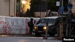 FILE - A soldier of the Israeli army stands next to a military vehicle in a street near the building where the Al Jazeera office was stormed and closed, in Ramallah, in the Israeli-occupied West Bank, Sept. 22, 2024. 