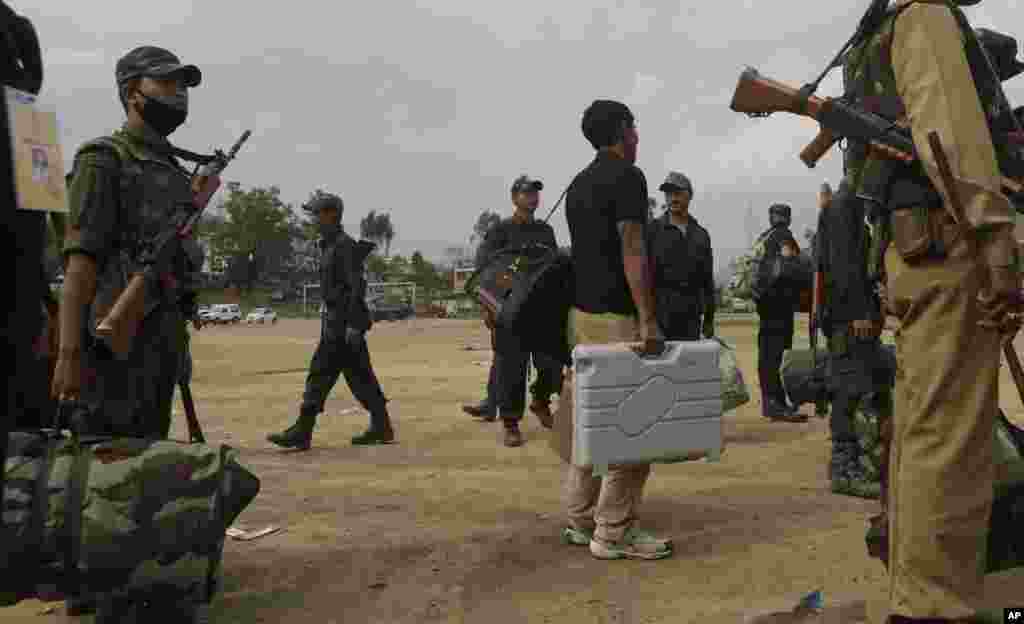 A polling official, center, carries an electronic voting machine as he and security personnel wait for vehicles to go to respective polling centers on the eve of the second phase of Indian parliamentary elections at Senapati, in north eastern Manipur stat